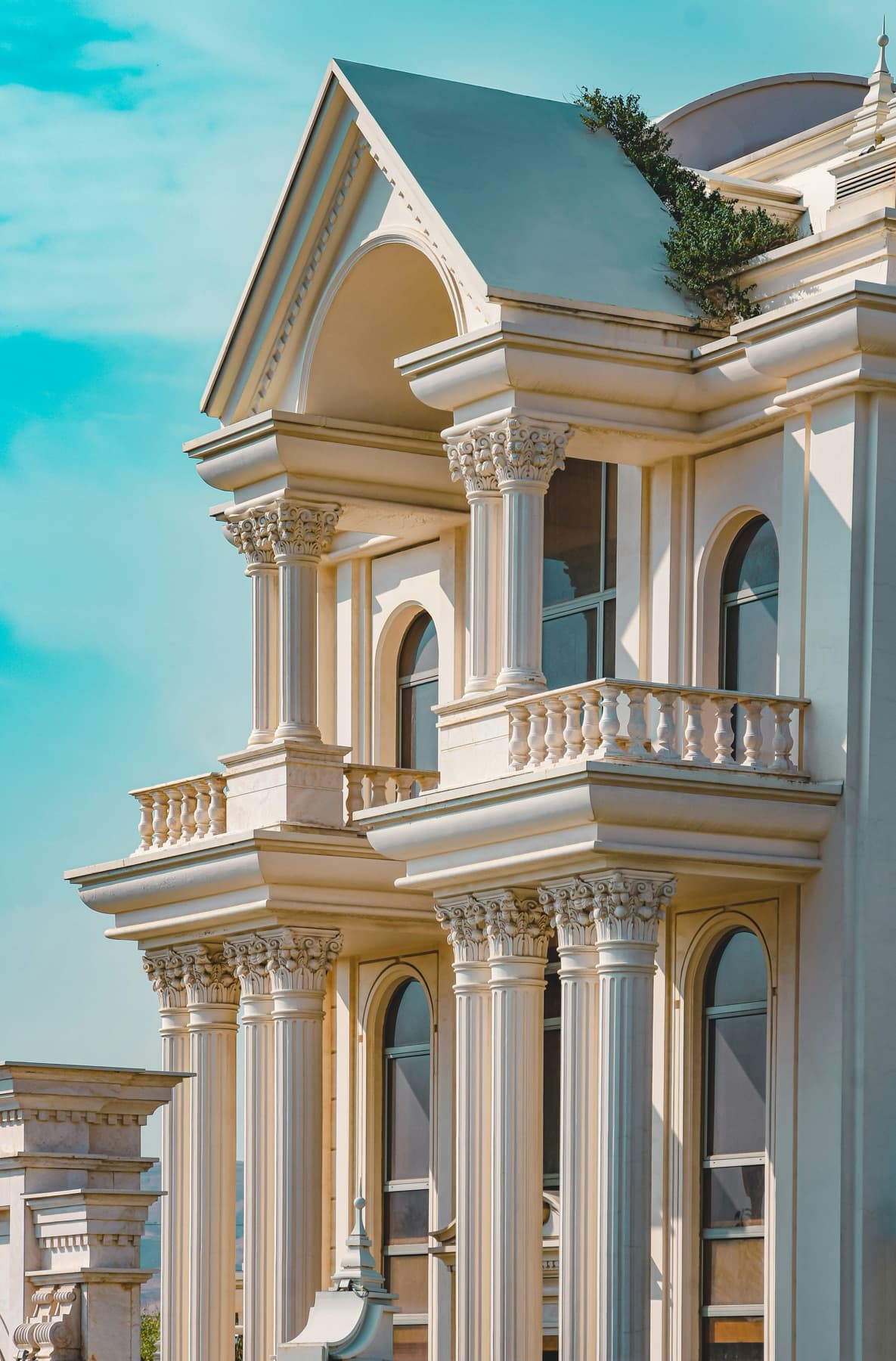 Neoclassical cream facade with Corinthian columns, balustraded balconies and arched windows