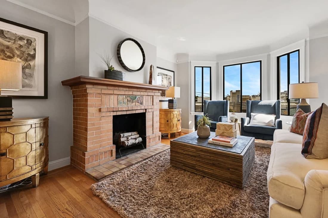 Living room at 1817 19th Street with a brick fireplace, bay windows and city views